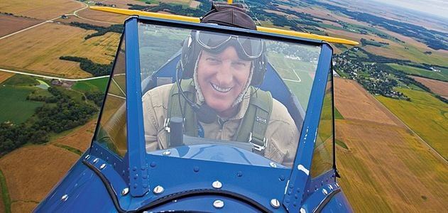 photo of biplane pilot in the sky looking into the windshield from the fuselage