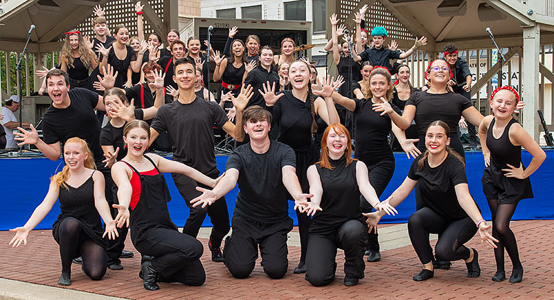 large group of youth performers, all in black, performing outdoors